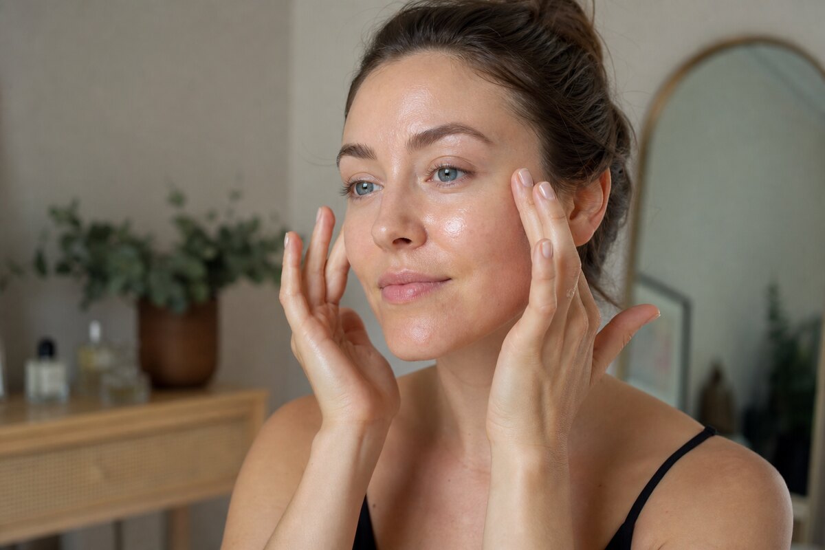 American woman gently pressing hydrated skin with both hands after applying a hydrating serum